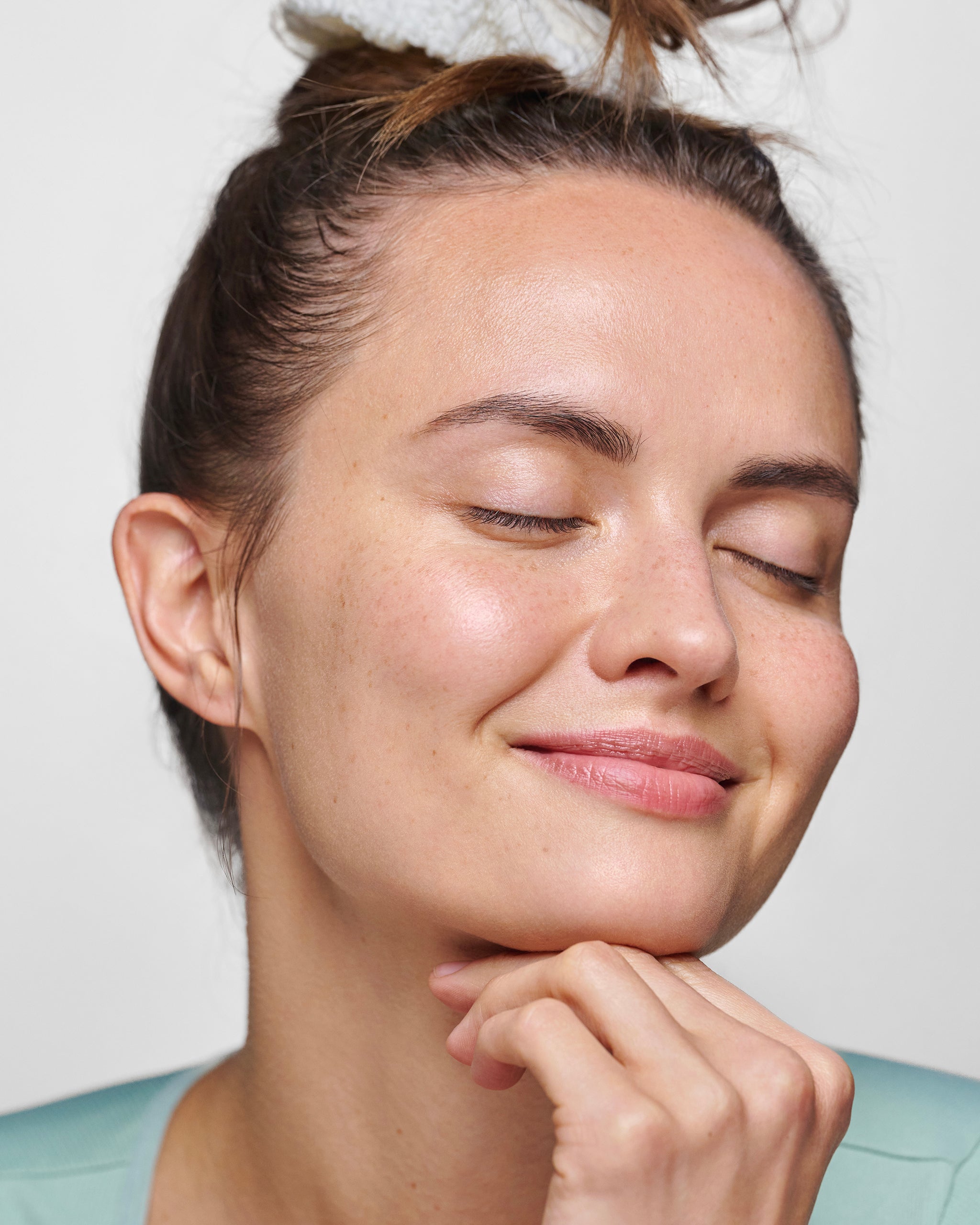 Smiling model with eyes closed and one hand under chin