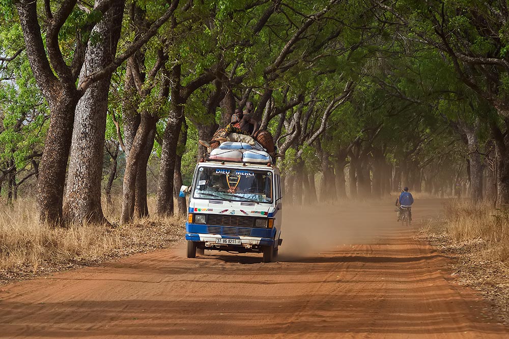 bush-taxi-driving-through-alley-of-trees-banfora-burkina-faso-africa-featured