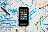 An iPhone surrounded by crayons