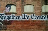 A brick wall with the words ‘Together We Create’ on it