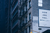 ‘How are you, really?’ poster on a side of a building. Photo by Des Récits on Unsplash