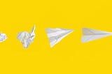 Ball of paper turning into a paper airplane on yellow background.