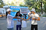 Two people stand nearby a life-sized animated cutout holding a placard to educate passersby about human trafficking.