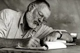 Black-and-white photo of Ernest Hemingway writing in Kenya