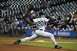 Baseball player pitching in front of stadium fans.