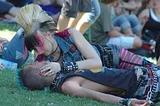 Two punks in love, on the grass in a crowd. Seemingly in a park