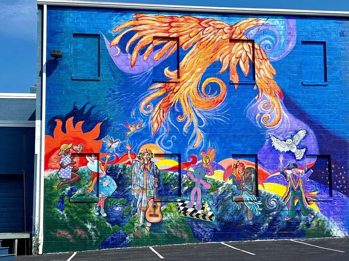 Mural with phoenix rising; six figures release birds to the sky