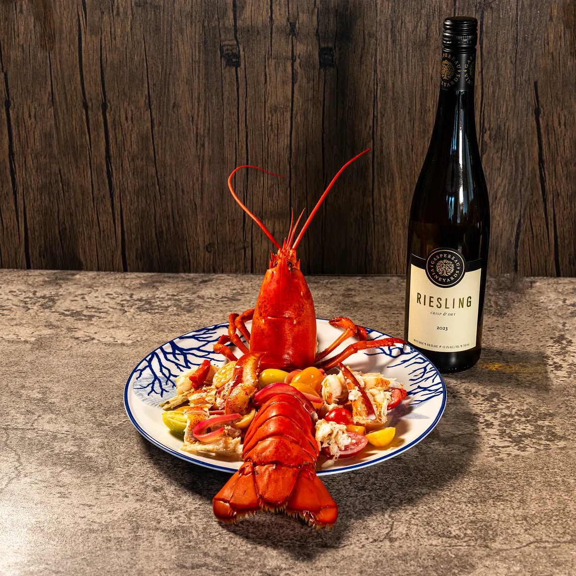 An image of catalan-style lobster with a bottle of Riesling wine