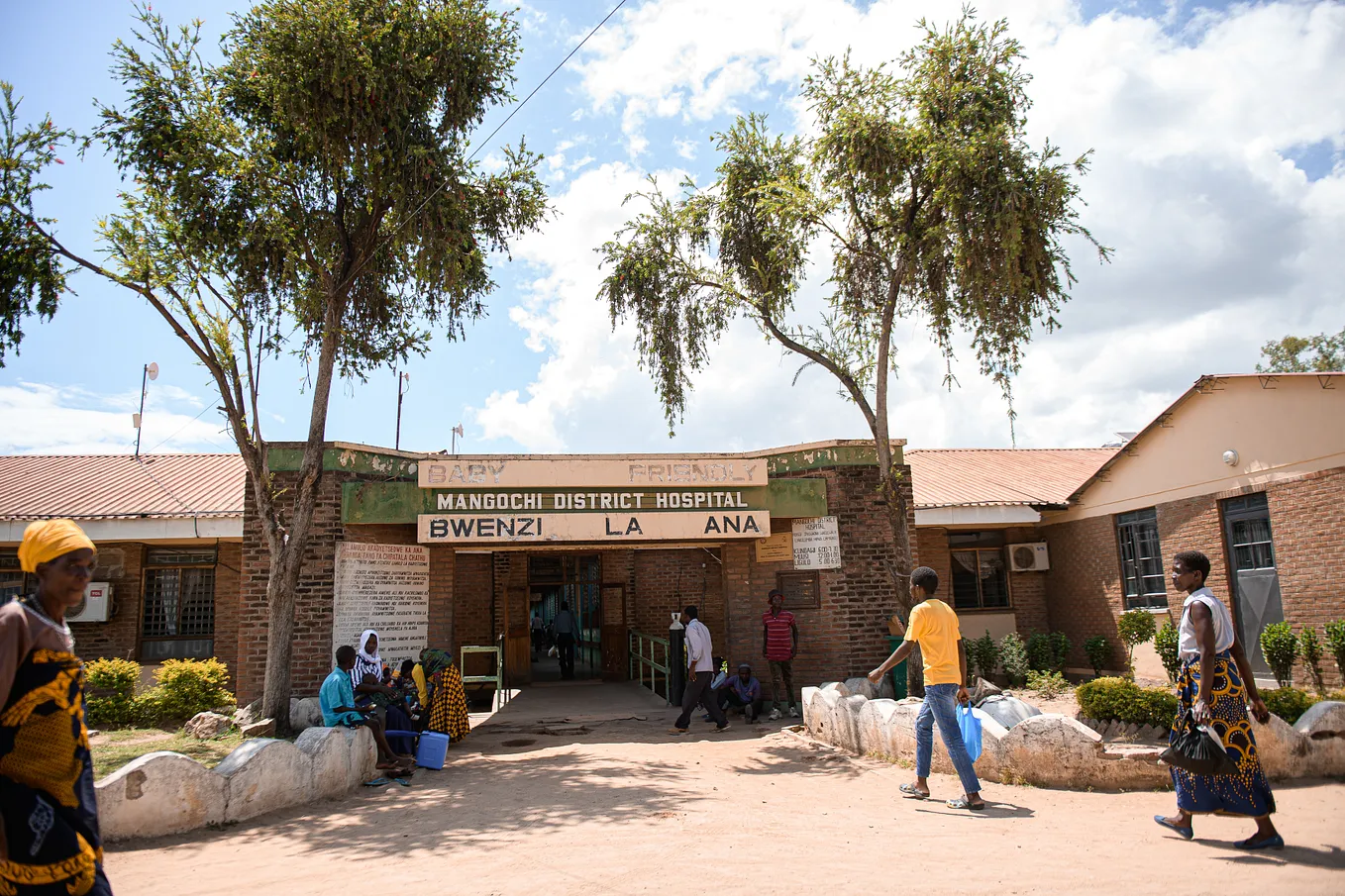 People walk by the outside of the Mangochi District Hospital.