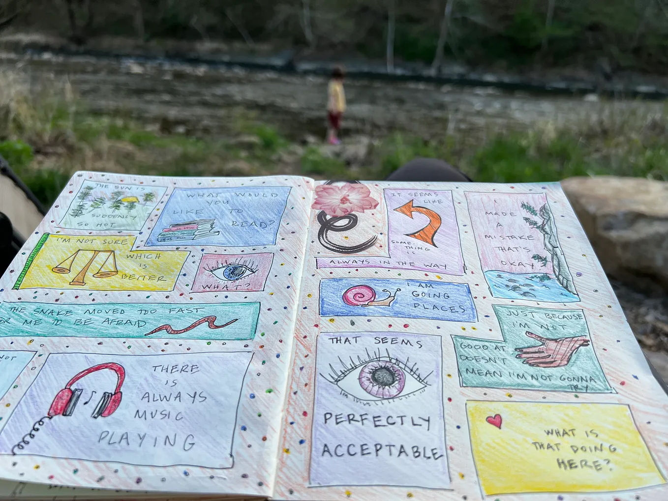 A notebook covered in colorful doodles, background of a river
