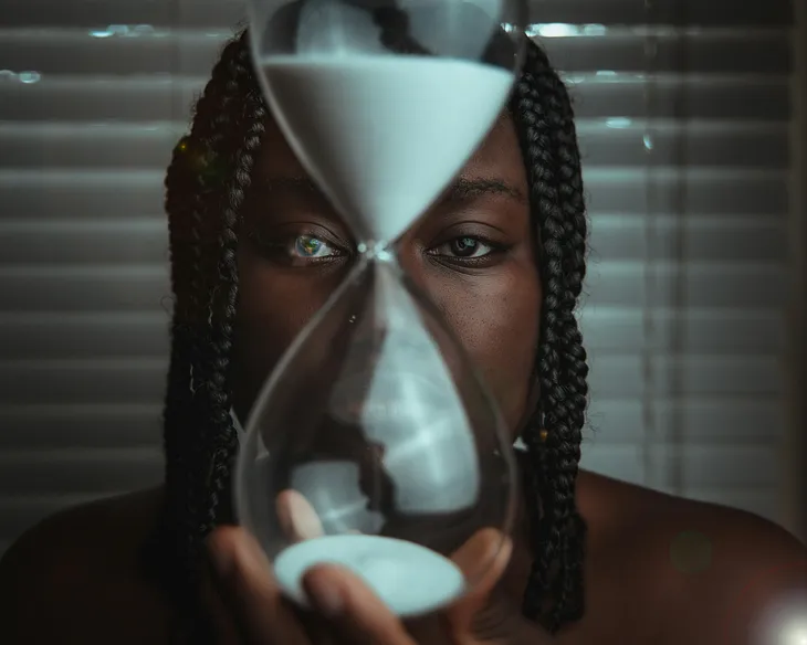 A person holding a hourglass with white sand inside.