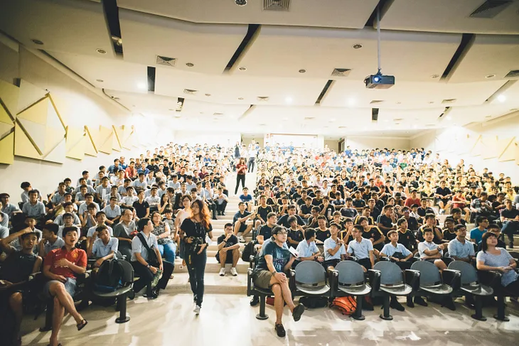 An image of a crowd gathered in a large presentation room.