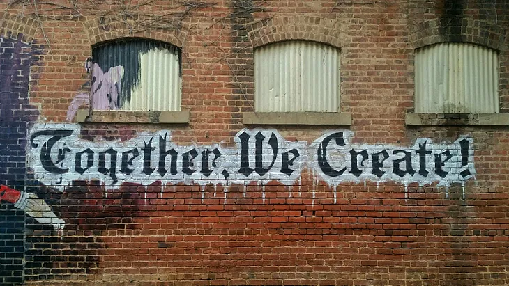 A brick wall with the words ‘Together We Create’ on it