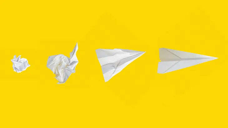 Ball of paper turning into a paper airplane on yellow background.