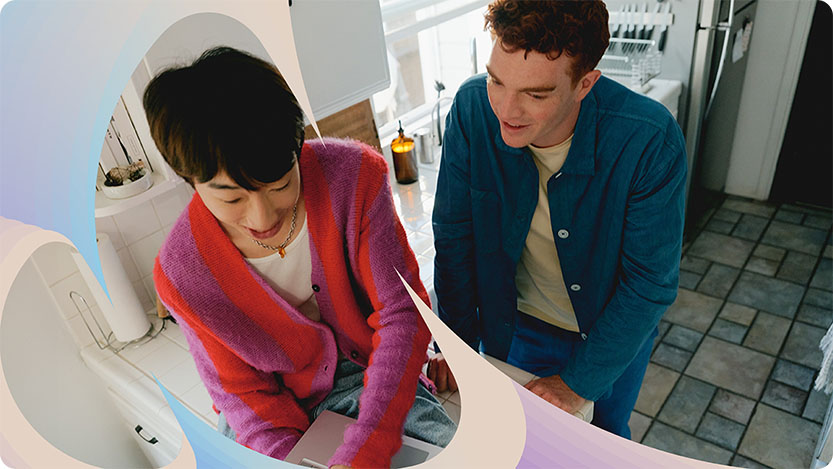 Two people in a kitchen working using a laptop.