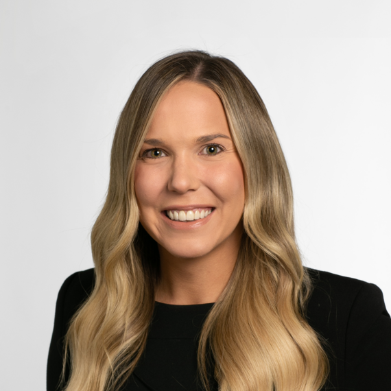 Woman with long blonde hair, smiling, wearing a black top, positioned against a plain white background.