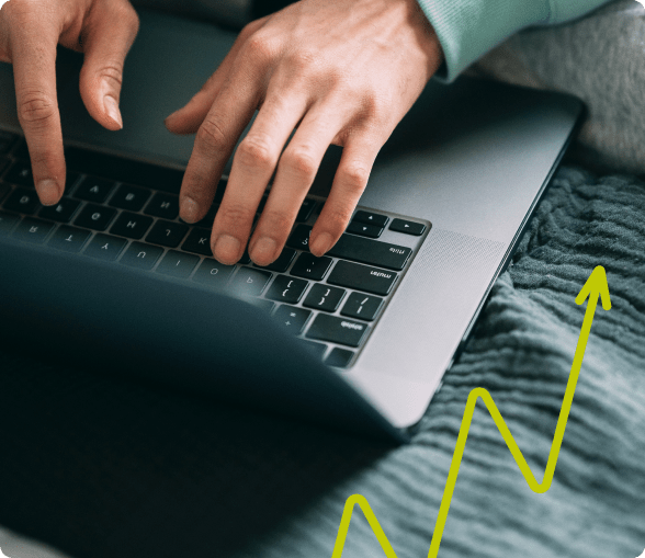 hands typing on a laptop resting on a blanket