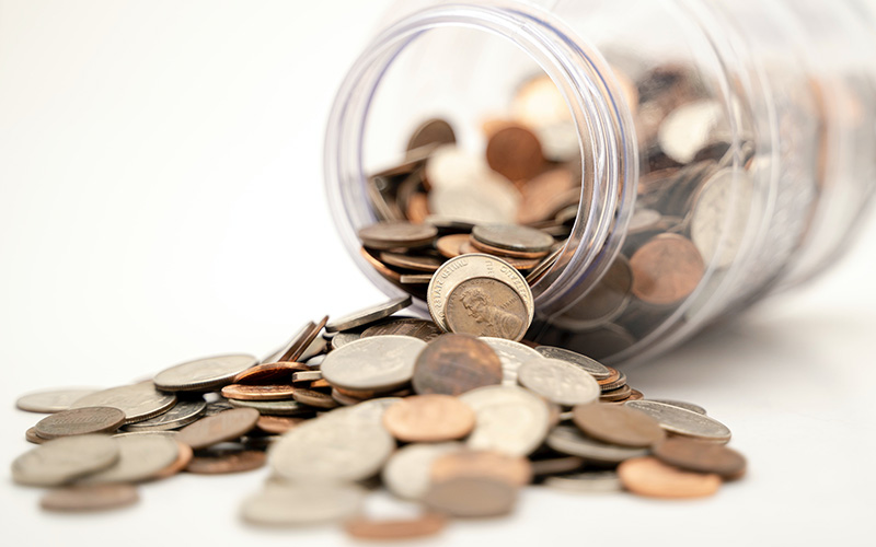 A jar full of pennies, tipped over with some spilling out.