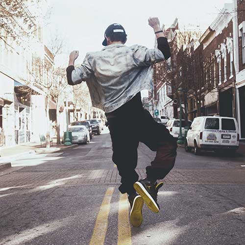 A teenager dancing down the street in celebration