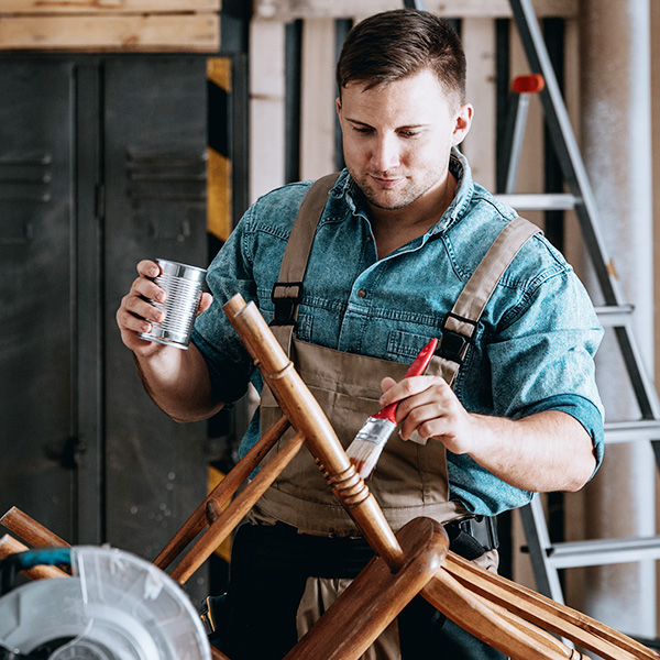 Man painting wooden chair in a workshop