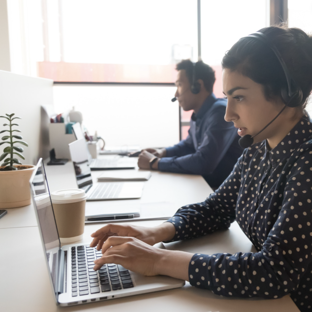 Two people wearing headphones sitting at laptop computers.