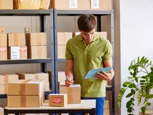 Small business owner viewing his tablet, checking a package to ship.