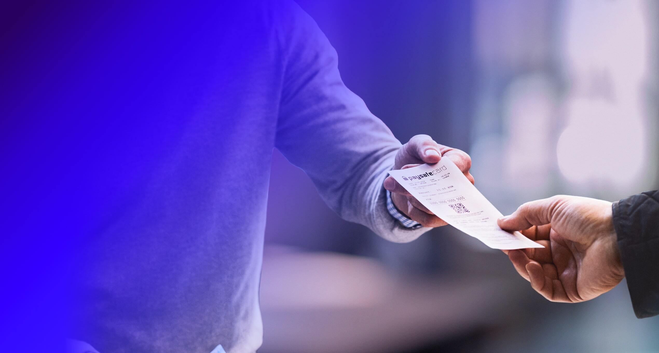 Close up on the hands of two people. One handing a paysafecard to the other.