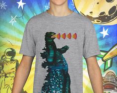 a young boy wearing a t - shirt with an image of a dinosaur on it