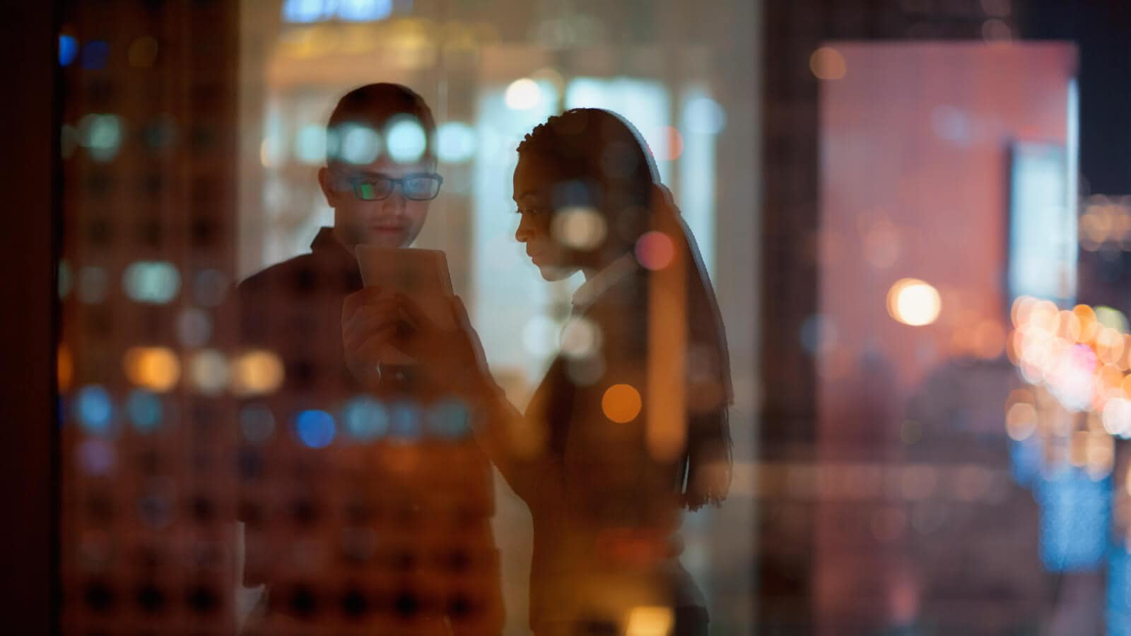 Coworkers looking at tablet in office at night