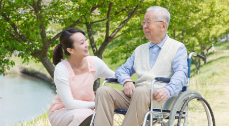 a caregiver and senior in a wheelchair smiling