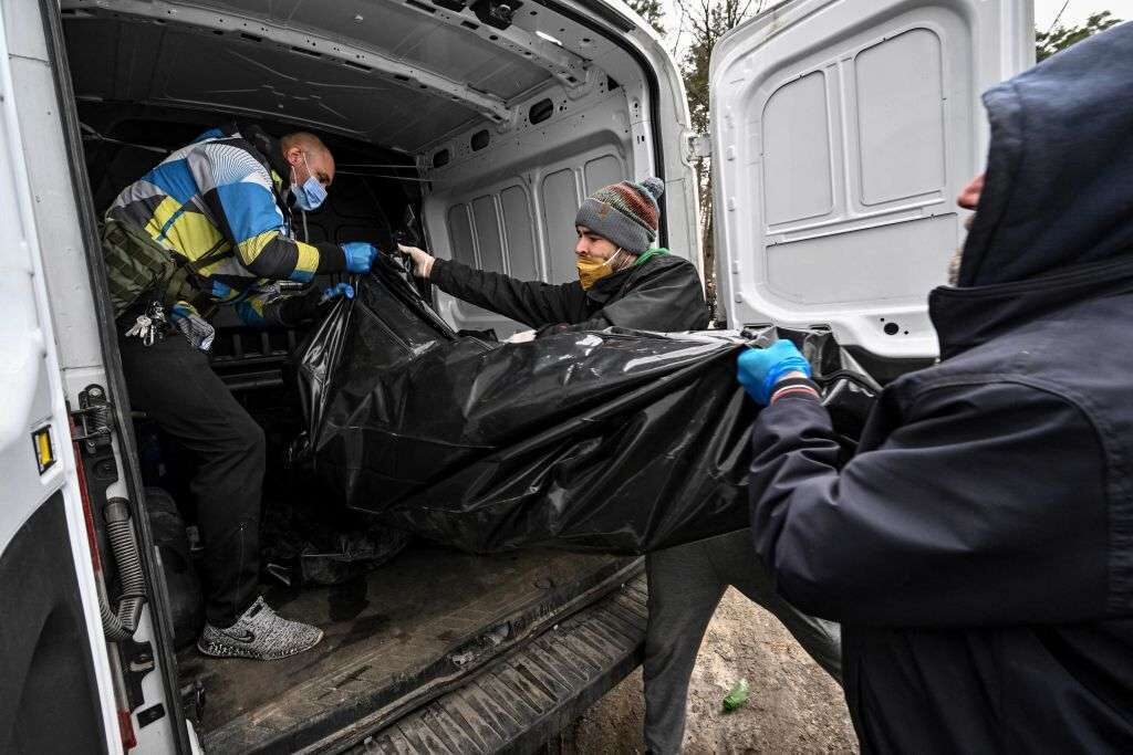 Policemen and city workers load a vehicle Tuesday with bodies found in the Ukrainian town of Bucha after Russian troops withdrew.