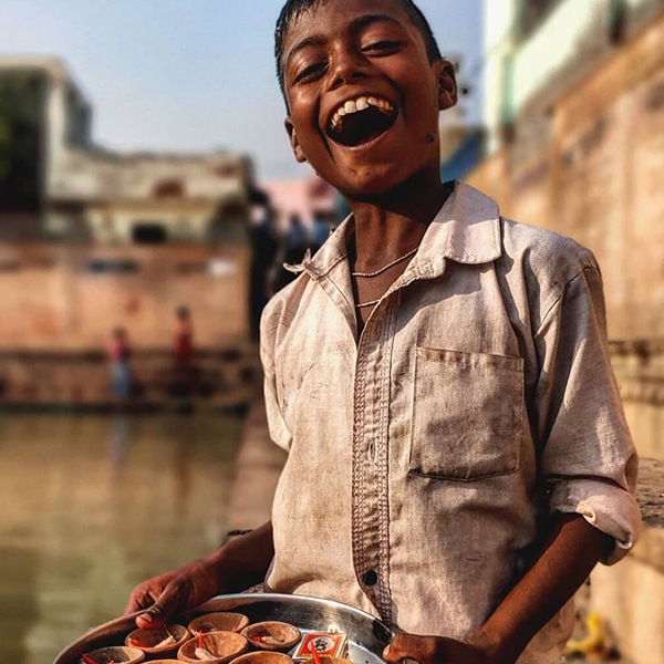 A young boy smiling at the camera holding a pan with cookies and matches