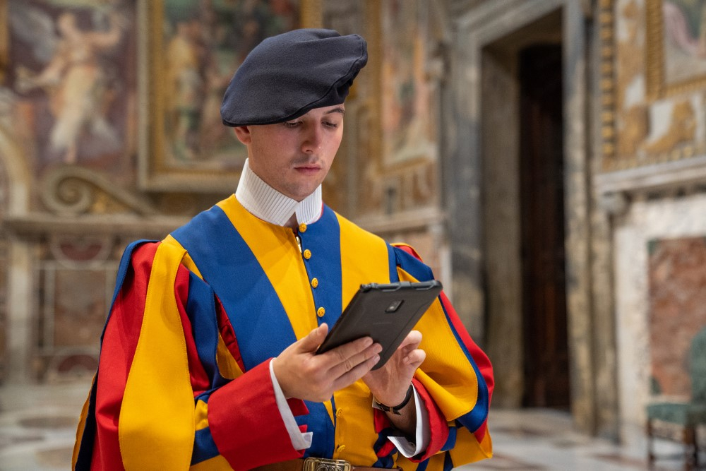 Person in Vatican uniform holding a rugged Samsung tablet