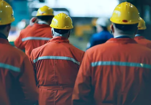 workers  helmets at the factory, view from the back, group of workers,  change of workers in the factory, people go in helmets and uniforms for an industrial enterprise