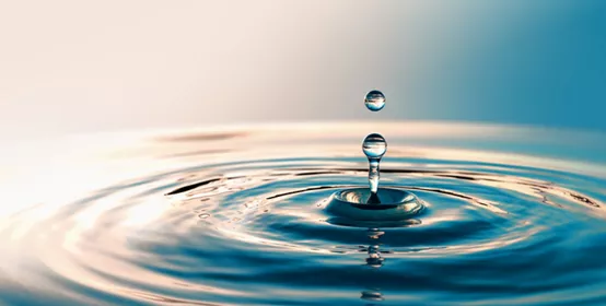 Clear water drop creating ripples on water