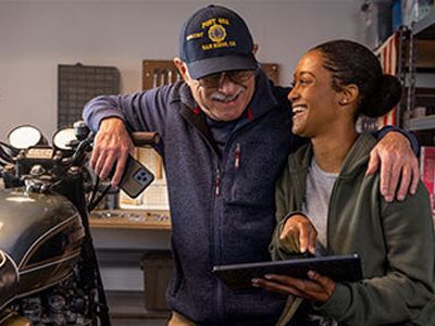 A military man and a girl smiling looking a tablet