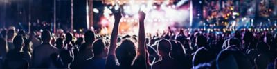 A concert crowd cheers from the back of the venue.