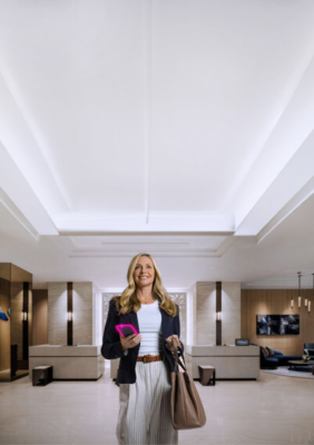 A woman stands in the lobby of a Hilton hotel with a bag in her hand.