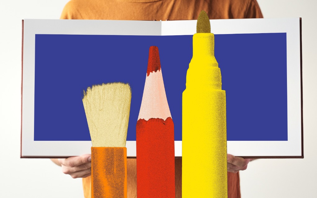 Person holding a book with large writing tools in the foreground