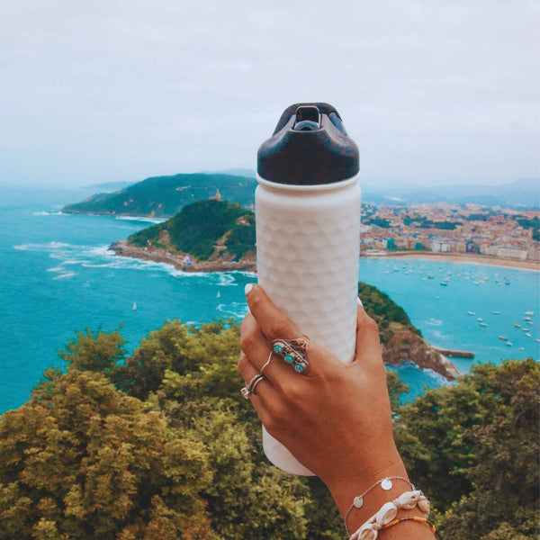 Woman holding a white water bottle over a bay