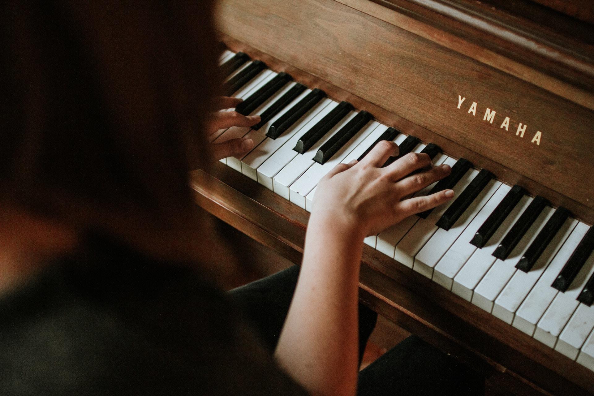 A piano player addresses their instrument with their fingers poised over the black keys.