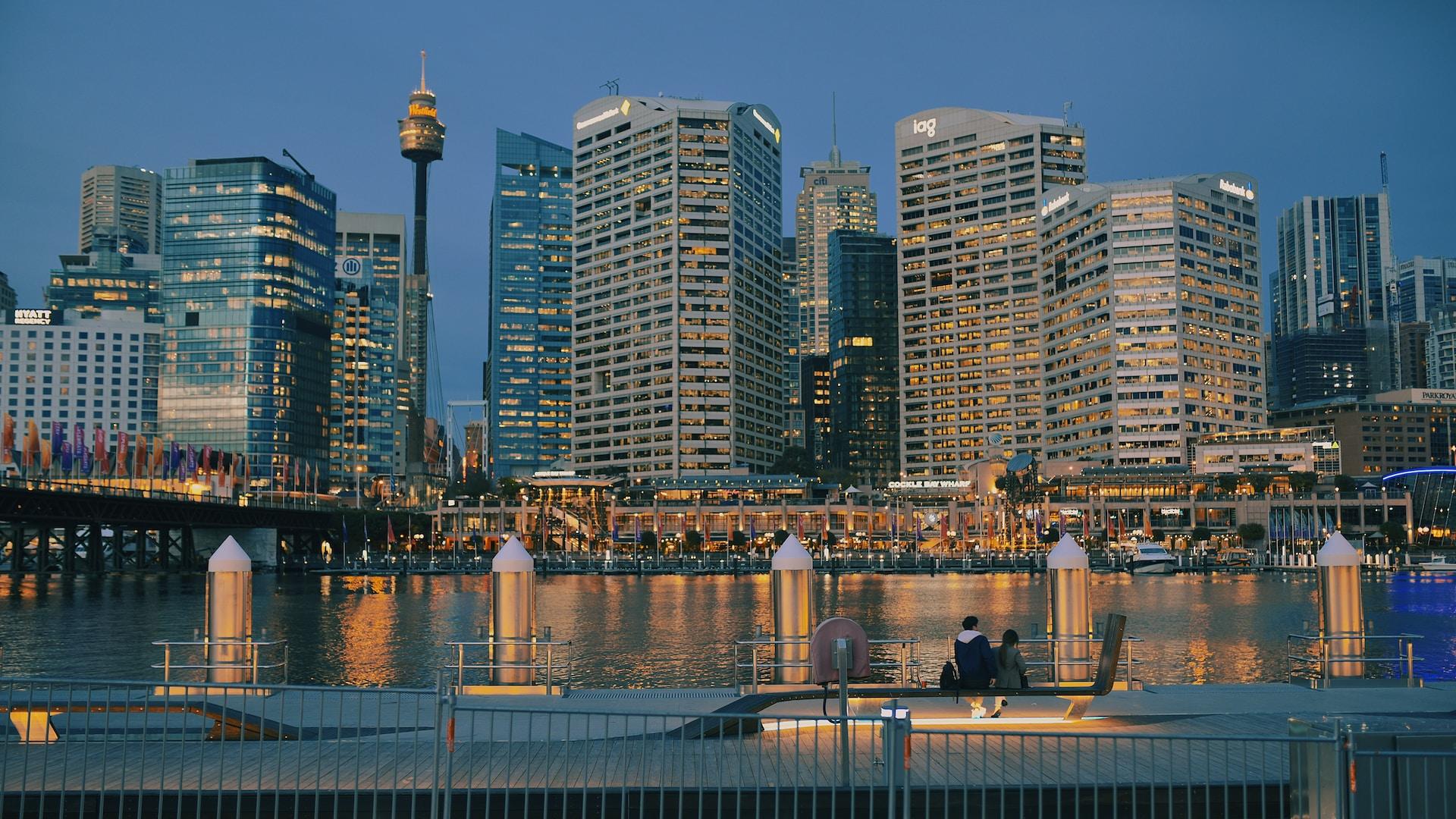 A view of Darling Harbour at dawn, as the sky begins to lighten and all the buildings are still lit up.