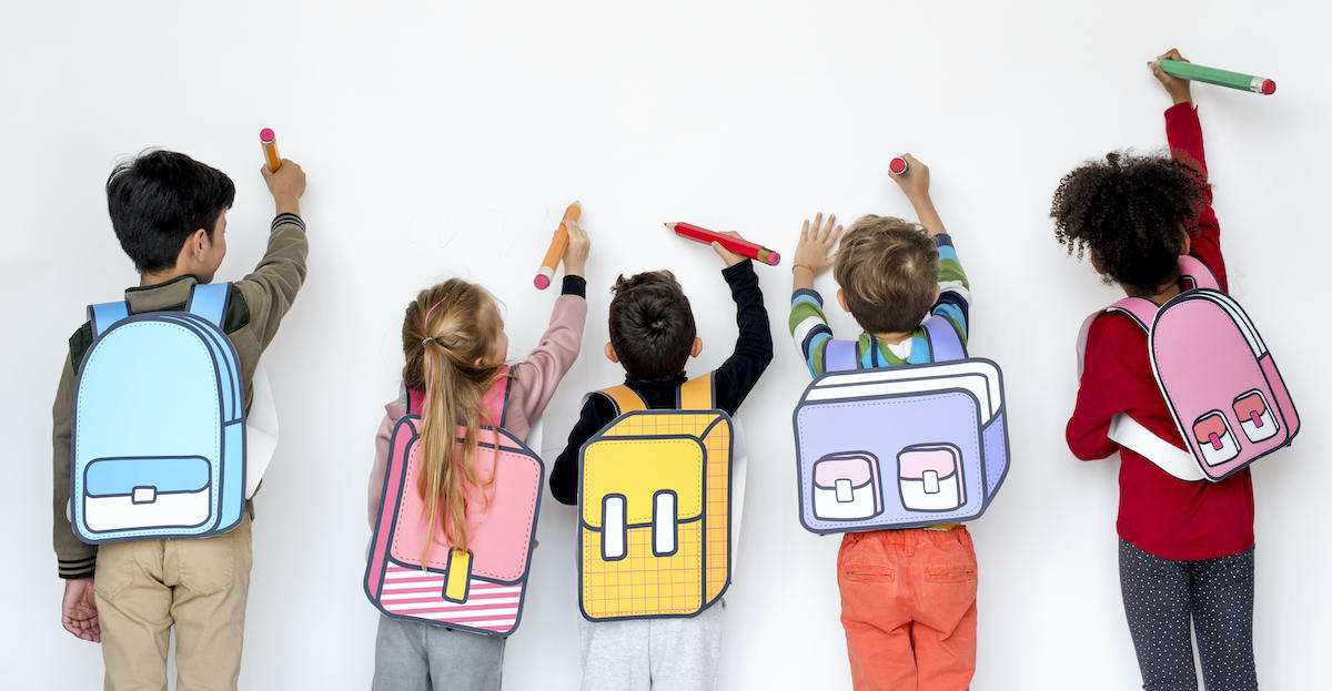 Jeunes écoliers de dos, portant des sacs à dos et écrivant sur un tableau blanc.