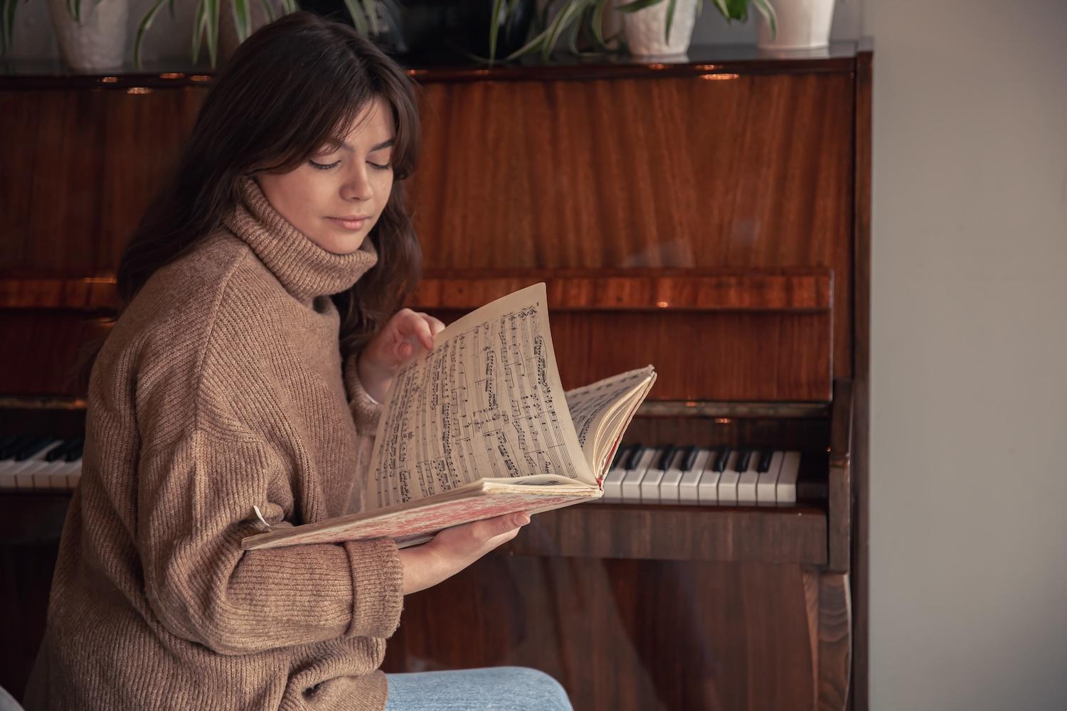 Une jeune femme regarde des partitions de piano. 