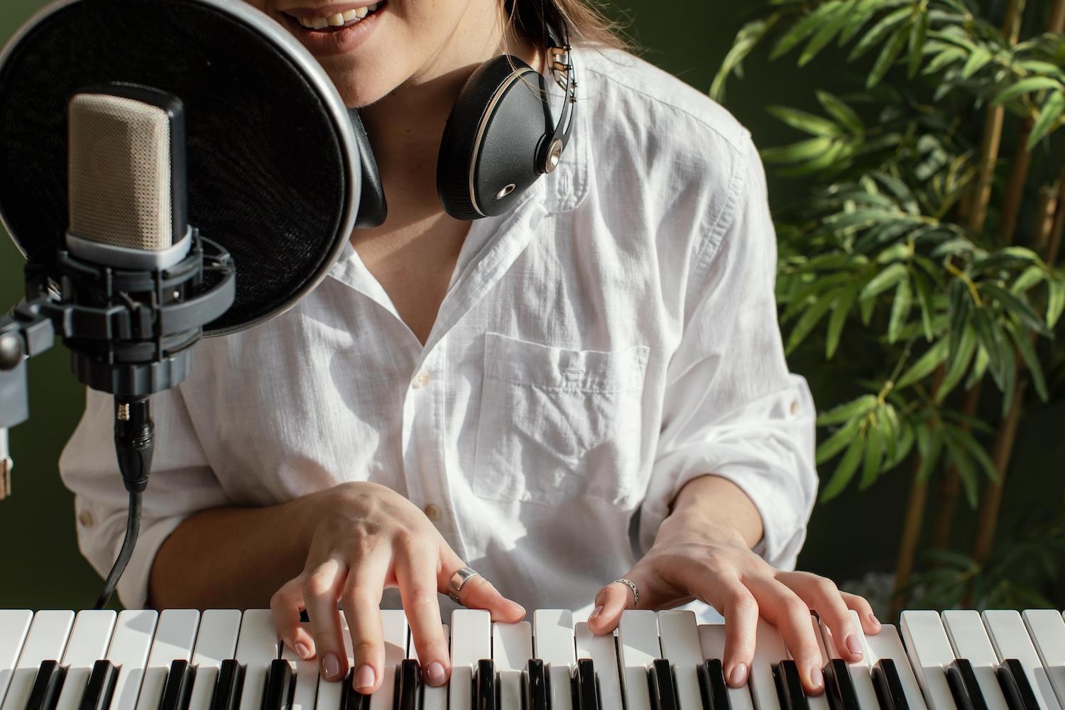 Une jeune femme joue et chante au micro avec un casque autour du cou.