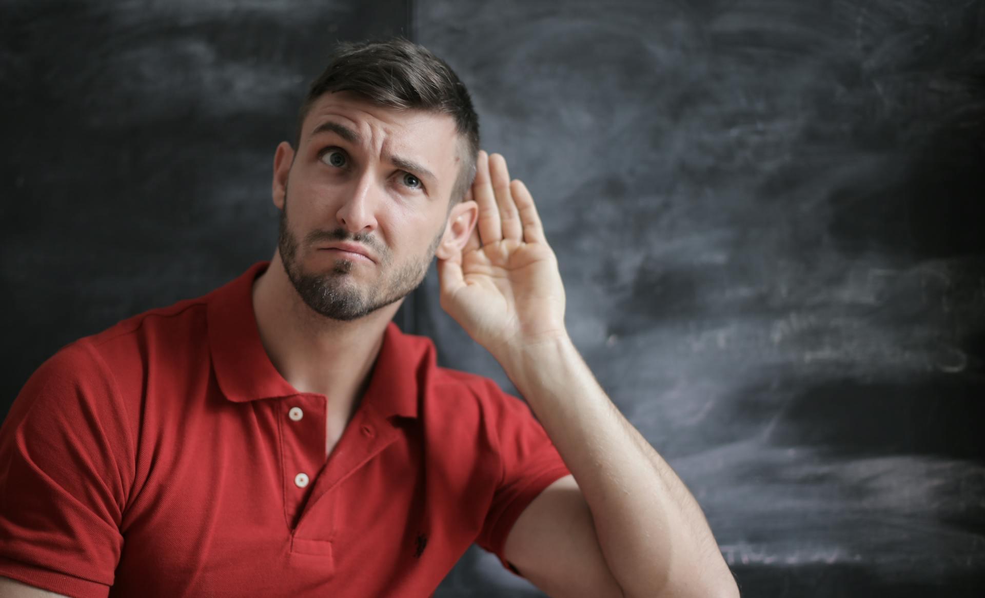 Un homme tendant l'oreille pour pratiquer l'écoute active. 