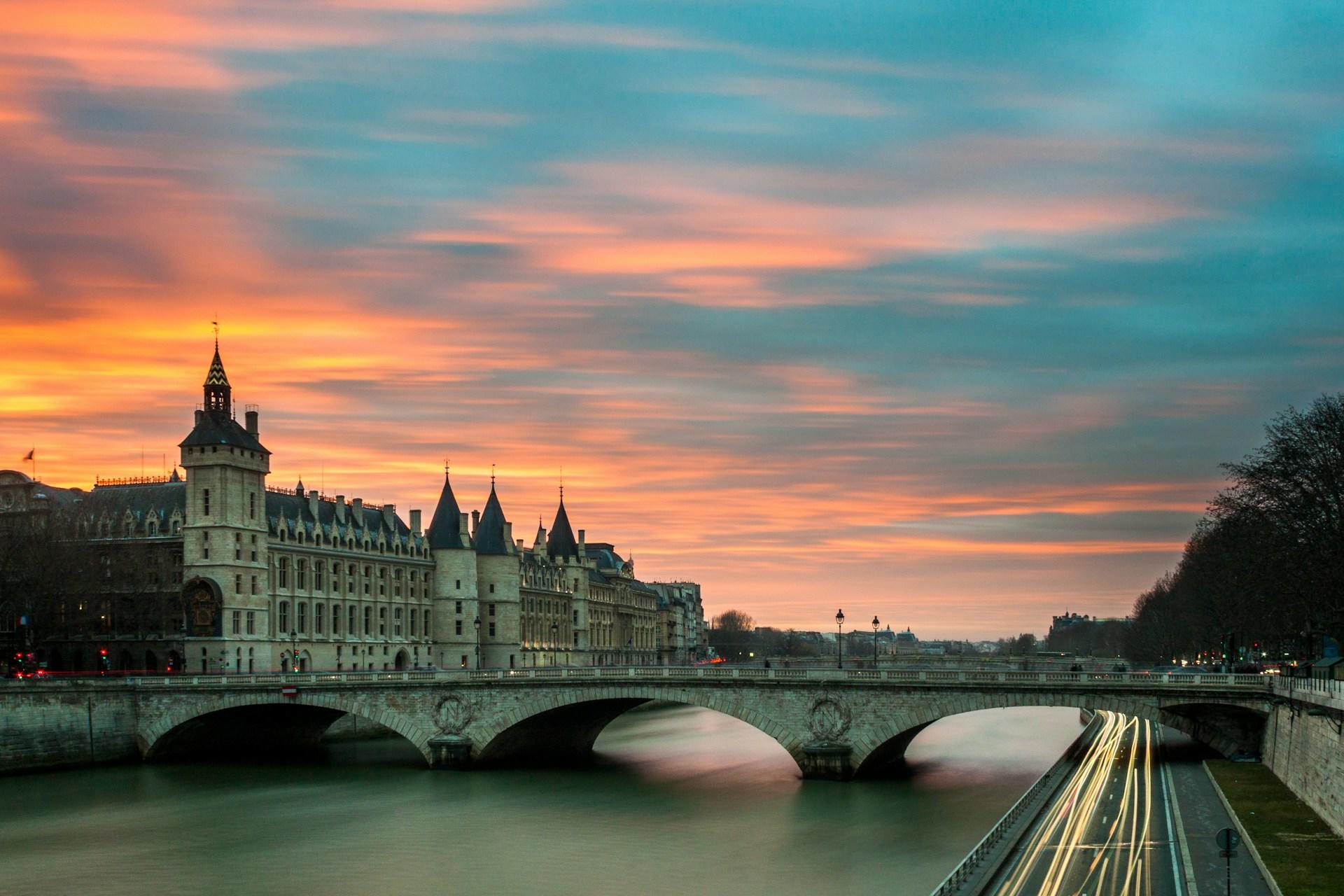 Orange sunrise over a river and a white stone building.