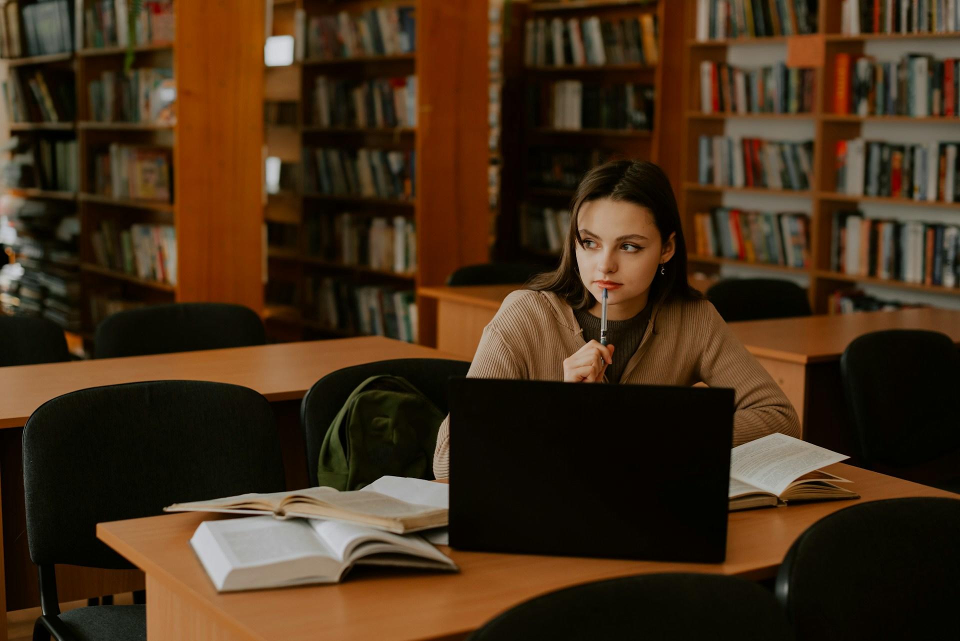 women studying with a computer and books at a library