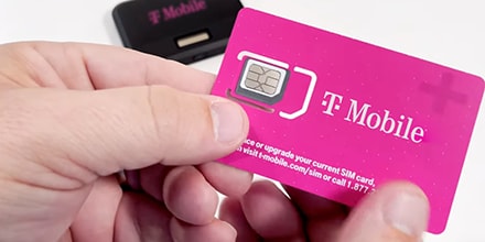 Hand holding magenta T-Mobile SIM card