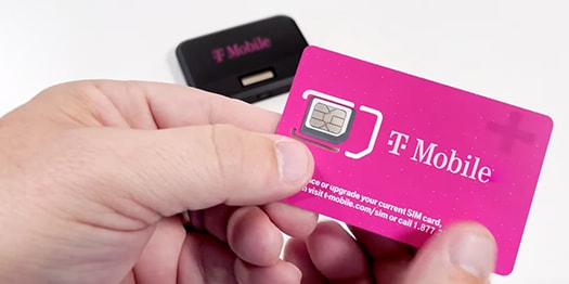 Hand holding magenta T-Mobile SIM card